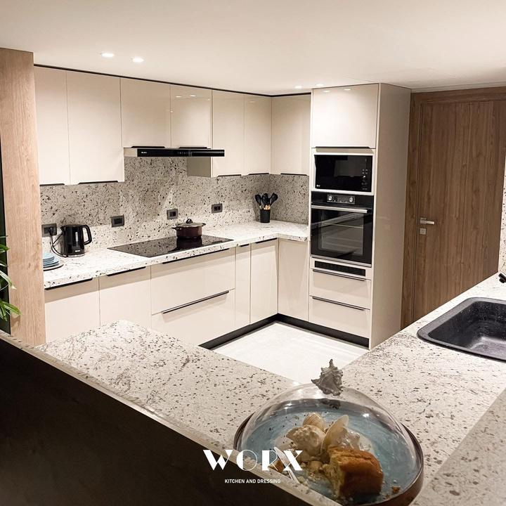 Cream gloss U-shaped kitchen with granite worktops and built-in ovens