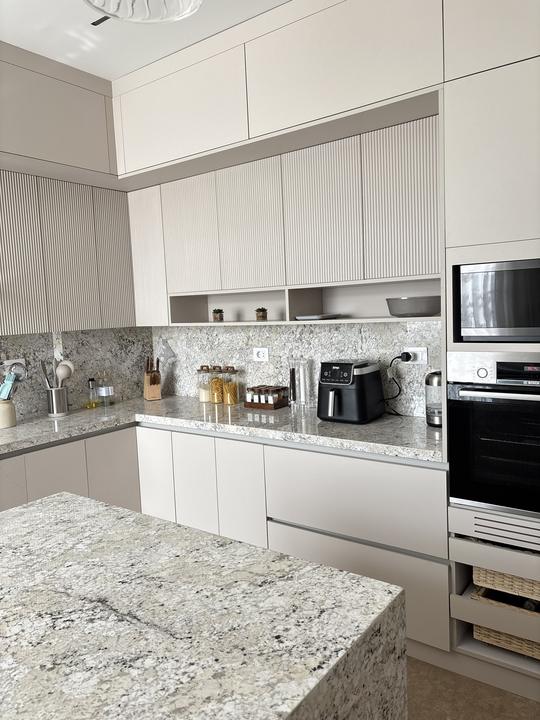 Fluted beige kitchen with open shelving and built-in ovens
