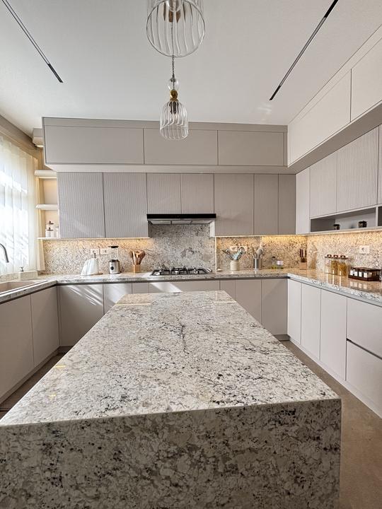 Beige fluted kitchen with granite waterfall island
