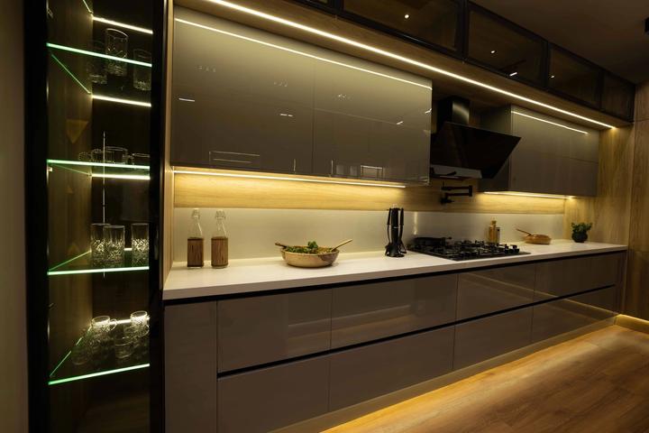 Grey gloss kitchen at night with LED lines and a lit glass display column