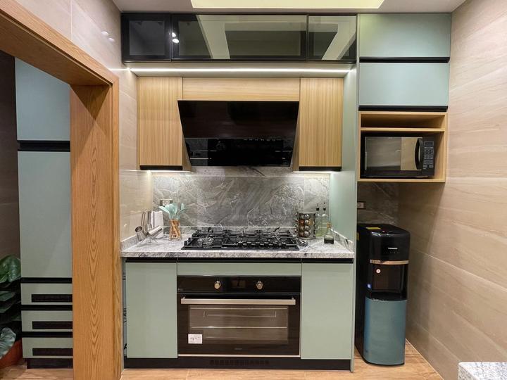 Mint green and oak kitchen with grey marble backsplash and built-in oven