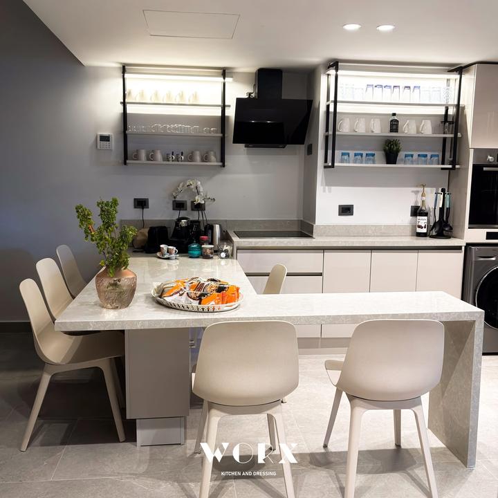 Stone dining peninsula with lit black-framed shelves and hood