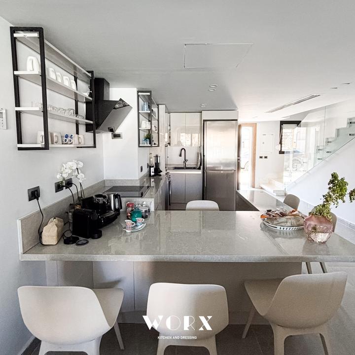 Peninsula kitchen with open shelves looking toward a glass staircase