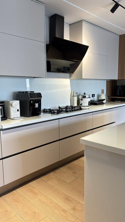 Handleless white kitchen with angled black glass hood