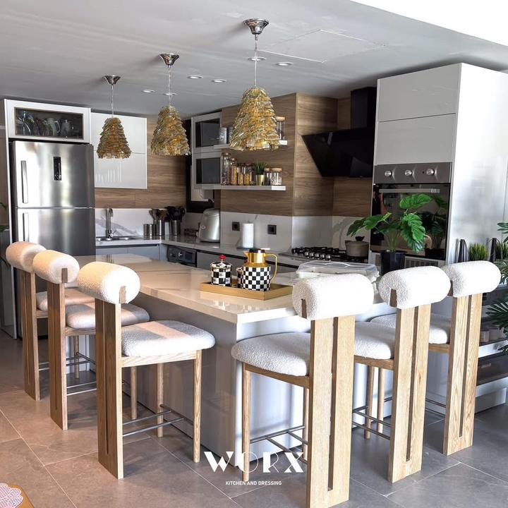 Open kitchen with gold pendant lights and bouclé stools
